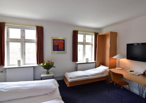 a hotel room with two beds and a desk at Hotel Schaumburg in Holstebro