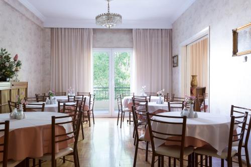 uma sala de jantar com mesas e cadeiras e uma grande janela em Anesis Hotel em Kozani