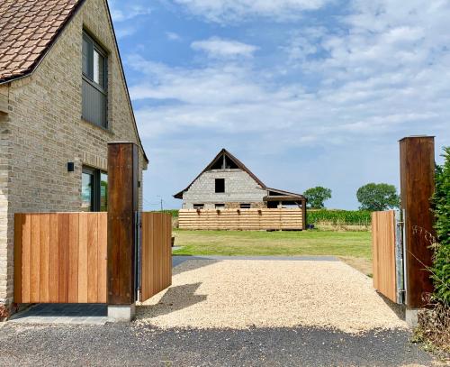 a house with a wooden gate and a barn at Vakantiewoning Ter Luyghem in Houthulst