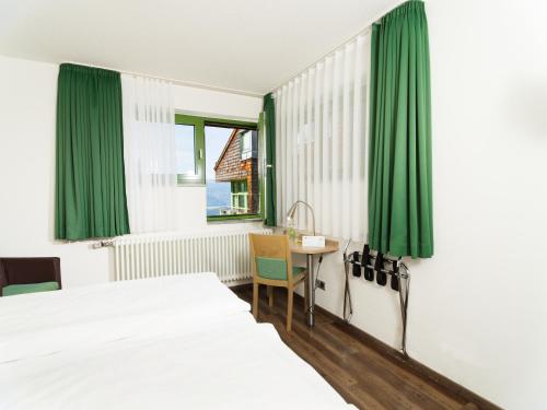 a bedroom with two beds and a table and green curtains at Haus Maria Lindenberg in Sankt Peter