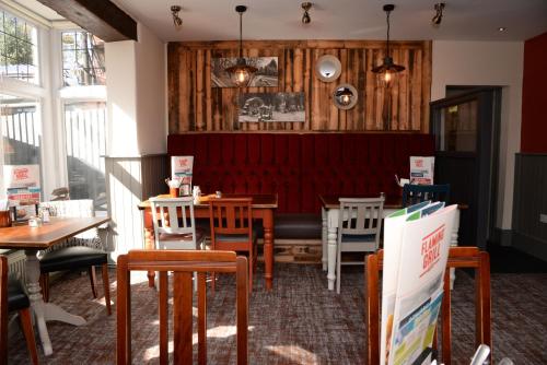 a restaurant with tables and chairs and a red bench at Southern Cross in Watford