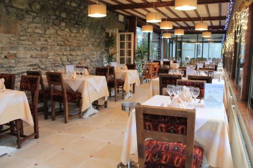 a restaurant with white tables and chairs and a stone wall at Manoir de la Roche Torin, The Originals Relais (Relais du Silence) in Courtils