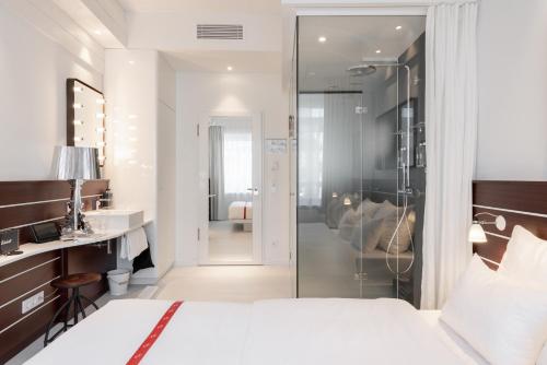 ein Schlafzimmer mit einem Bett und ein Badezimmer mit einer Dusche in der Unterkunft Ruby Lotti Hotel Hamburg in Hamburg