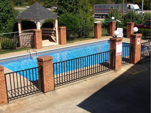 a swimming pool with a fence and a gazebo at Royal Inn - Anniston in Anniston