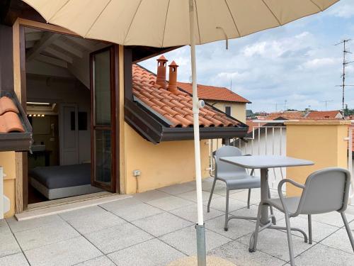 a table and two chairs and an umbrella on a patio at Porta Ronca - B&B, Suites & Apts in Rho