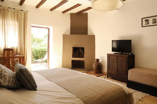 a bedroom with a bed with a television and a fireplace at Le Petit Hôtel du Flouka in Lalla Takerkoust