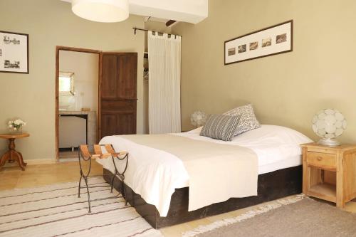 a bedroom with a bed with white sheets and a table at Le Petit Hôtel du Flouka in Lalla Takerkoust