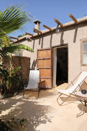 a patio with two chairs and a house at Le Petit Hôtel du Flouka in Lalla Takerkoust