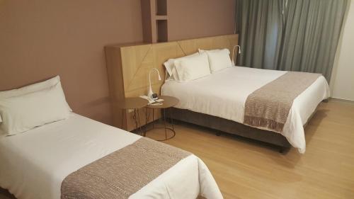 a hotel room with two beds and a side table at Brizo Salta in Salta
