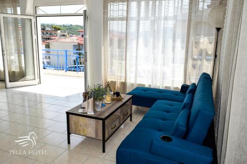 a living room with blue furniture and a large window at Pella Hotel - new in Neos Marmaras