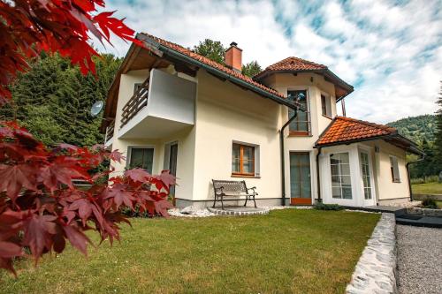 a white house with a bench in the yard at House of Adventure - The Base to explore Slovenia in Laze v Tuhinju