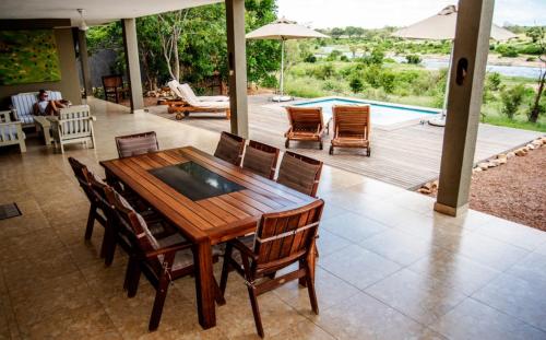 a wooden table and chairs in a patio with a pool at Crocodile Bend in Mpakeni
