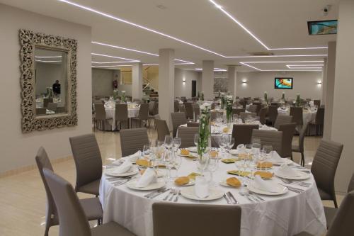 una sala de banquetes con mesas y sillas blancas y un espejo en Hotel Paraiso Granada, en Moraleda de Zafayona