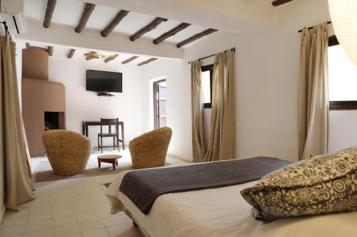 ein Schlafzimmer mit einem Bett und Stühlen sowie einem TV in der Unterkunft Le Petit Hôtel du Flouka in Lalla Takerkoust