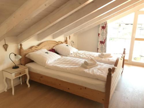 una camera da letto con letto in legno, lenzuola e cuscini bianchi di Haus Vincent a Grassau