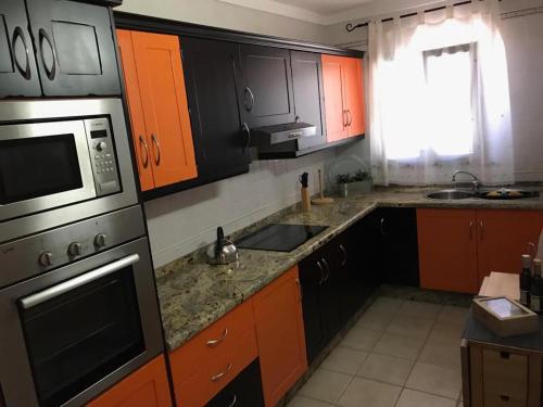 プラヤ・デ・サンティアゴにあるApartamento El Cascajoのキッチン(オレンジ&黒のキャビネット、シンク付)