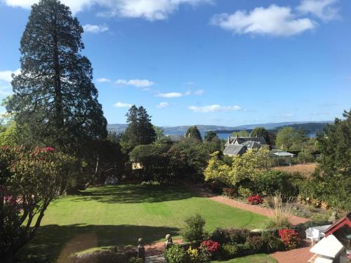 a large lawn in a garden with trees and bushes at Moorlands in Helensburgh