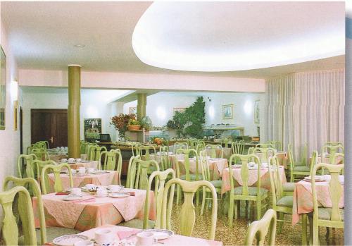 a dining room with tables and chairs and a room with pink tables at Hotel Piroga Padova in Selvazzano Dentro
