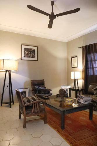 a living room with a table and a ceiling fan at Le Petit Hôtel du Flouka in Lalla Takerkoust