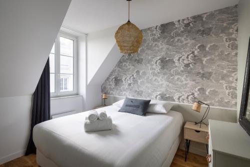 une chambre avec un lit blanc avec deux serviettes dessus dans l'établissement Le Cosy Breizh - Appt à St-Malo, à 1km de la plage, à Saint-Malo