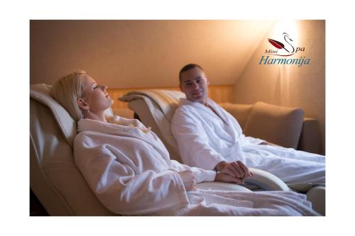 a man and woman sitting in chairs in a hotel room at Mini spa Harmonija in Zapyškis