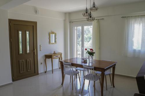 una sala da pranzo con tavolo, sedie e finestra di Maison fleurs a Diakopto