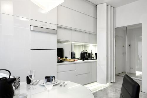 una cucina con armadi bianchi e tavolo bianco di 19 Dzielnica Kolejowa P&O Serviced Apartments a Varsavia