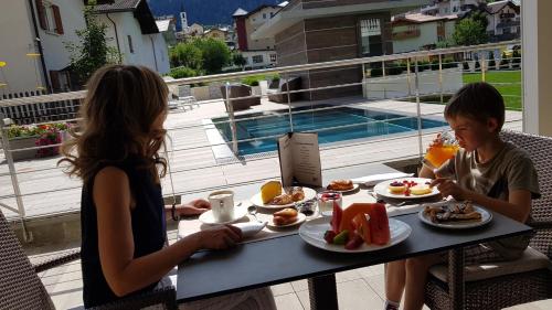 a boy and a girl sitting at a table with food at Dolce Avita Hotel Spa & Resort in Andalo
