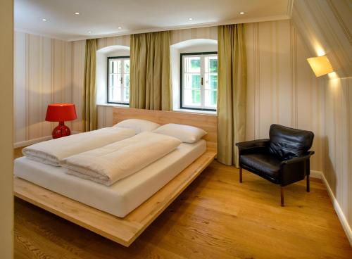 a bedroom with a large bed and a black chair at Waldach Villa in Thalgau