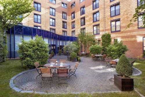 a patio with tables and chairs in front of a building at H4 Hotel Hamburg Bergedorf in Hamburg