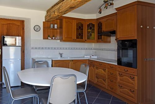 una cocina con armarios de madera y una mesa y sillas blancas. en Etang Lassalle en Lamazère