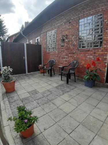 a patio with two chairs and a table and flowers at Pension Im Rehwinkel in Soltau