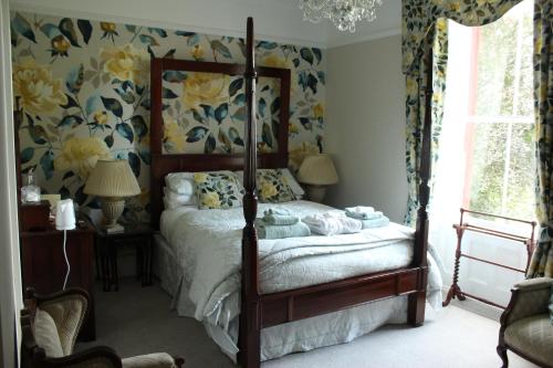 1 dormitorio con cama con dosel y papel pintado con motivos florales en Bank House B and B, en Penrith