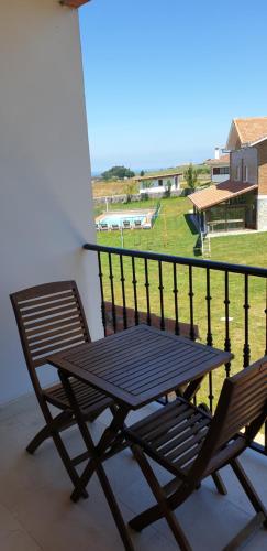a picnic table and two chairs on a balcony at Apartamentos La Pradera de Isla in Isla