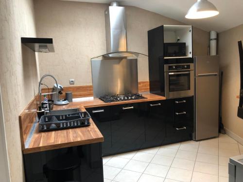 eine Küche mit Herd und Kühlschrank in der Unterkunft Spacieux appartement 2/6 pers 110m² proche CNPE in Lagnieu