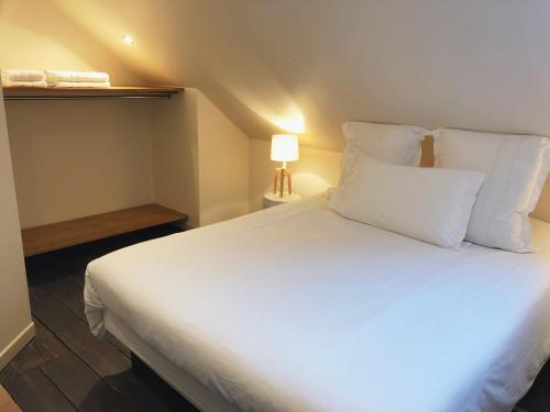 1 cama con sábanas blancas y almohadas en una habitación en Nuit en Ville Lille La Madeleine, en La Madeleine