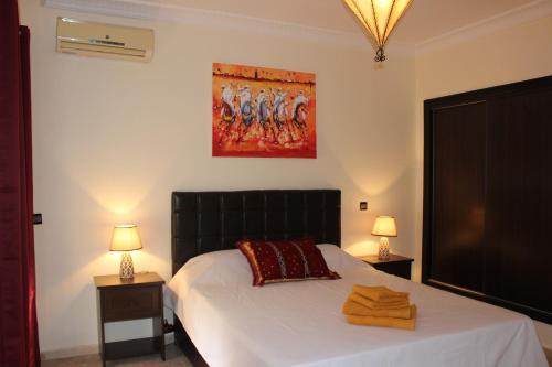 a bedroom with a bed and two lamps and a painting at Studio Salmiya Dune in Marrakesh