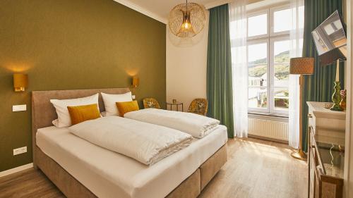 a bedroom with a large white bed with a window at Rochter Landhotel in Zeltingen-Rachtig
