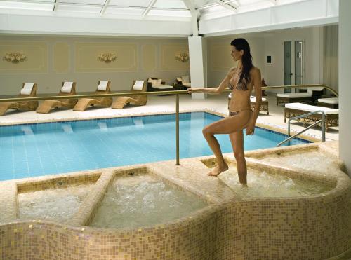 a woman in a bathing suit standing on the edge of a swimming pool at Hotel Terme Principe in Abano Terme