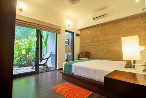 een slaapkamer met een bed en een glazen schuifdeur bij Villa Escondite - The Hotel in Sri Jayewardenepura Kotte