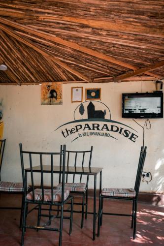 a table and chairs with a sign on a wall at The Paradise In Kilimanjaro in Moshi