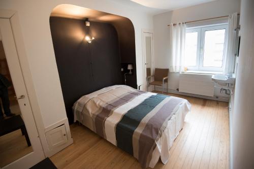 een slaapkamer met een bed, een wastafel en een raam bij Clos Normand in Nieuwpoort