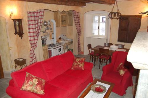 a living room with a red couch and a kitchen at Le Primule in Piedilago