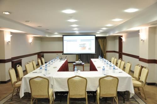 a conference room with a long table with chairs and a screen at Hotel Midi in Ankara
