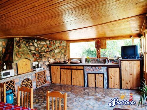 eine Küche mit Holzdecken und einer Theke mit einem TV in der Unterkunft Guest House Danny in Shabla