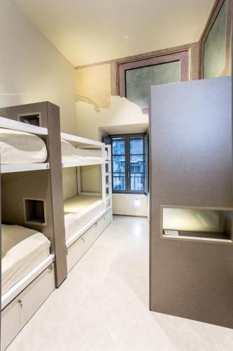 a room with bunk beds and a large window at Little Italy Hostel Ex Chiesa S Donato in Perugia