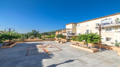 a large courtyard with trees and a building at Vacancéole – Le Domaine de Camiole in Callian
