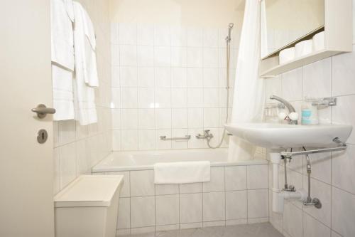 a white bathroom with a sink and a bath tub at PABS Résidences - Weinbergstrasse 68 (2ML) in Zurich
