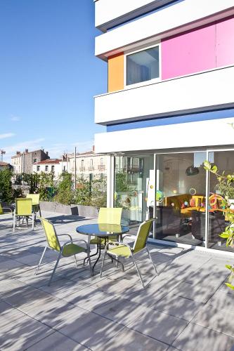a patio with a table and chairs in front of a building at Privilège Hôtel & Apparts Eurociel Centre Comédie in Montpellier