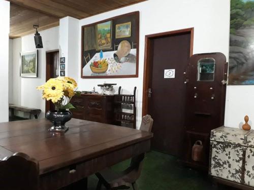 ein Zimmer mit einem Tisch mit einer Blumenvase darauf in der Unterkunft Pousada Mirante das Pedras in São Thomé das Letras
